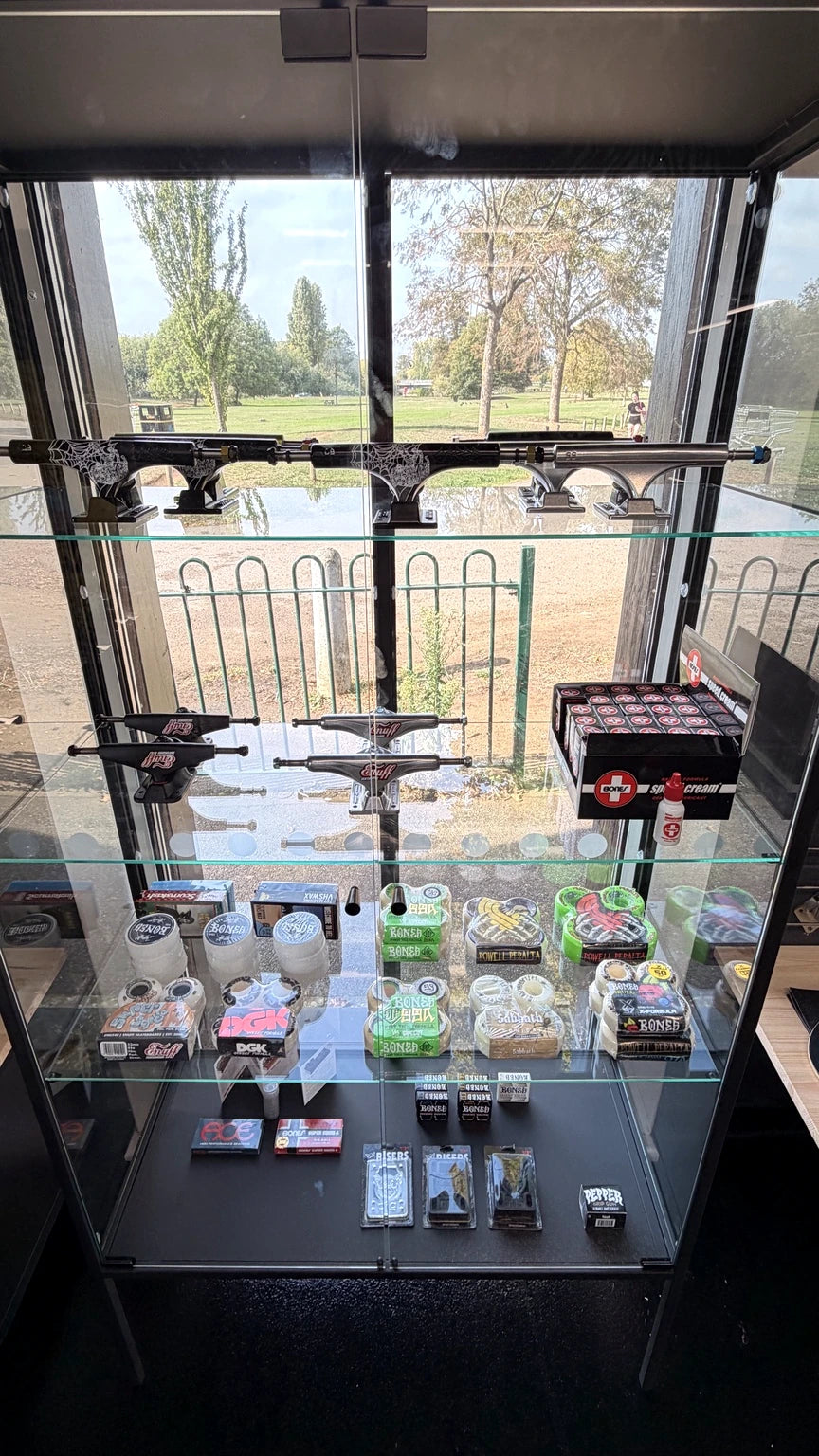 Real shop display with skateboard trucks, bearings, wheels and accessories; no BMX products shown